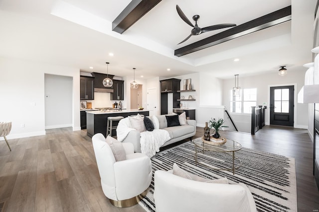 living room featuring a raised ceiling, beamed ceiling, ceiling fan, dark hardwood / wood-style floors, and sink