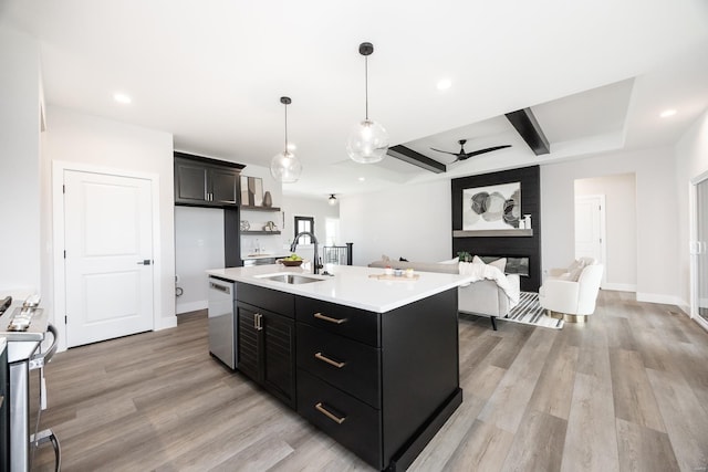 kitchen featuring ceiling fan, an island with sink, a multi sided fireplace, sink, and stainless steel appliances