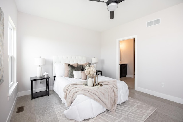 carpeted bedroom with multiple windows, ceiling fan, and ensuite bathroom