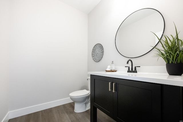 bathroom featuring wood-type flooring, lofted ceiling, vanity, and toilet