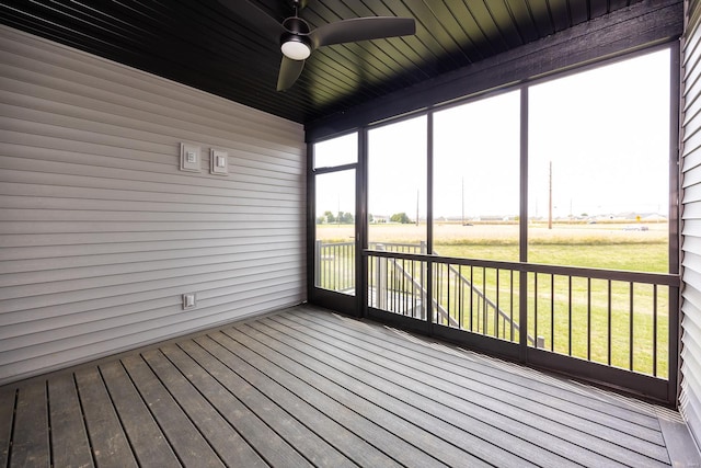 unfurnished sunroom with wooden ceiling, ceiling fan, a rural view, and a wealth of natural light