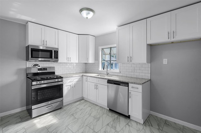 kitchen with light stone countertops, white cabinetry, sink, and stainless steel appliances