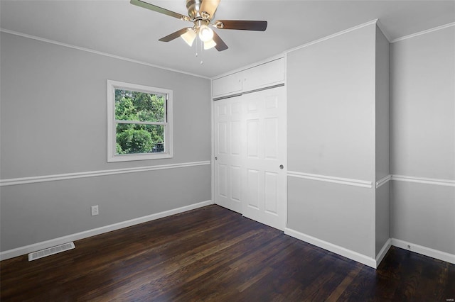 unfurnished bedroom featuring ornamental molding, dark wood-type flooring, ceiling fan, and a closet