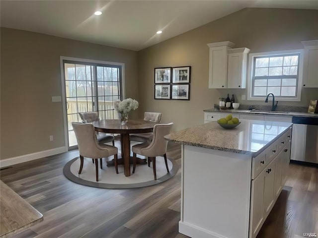 kitchen with a center island, white cabinets, stainless steel dishwasher, and lofted ceiling