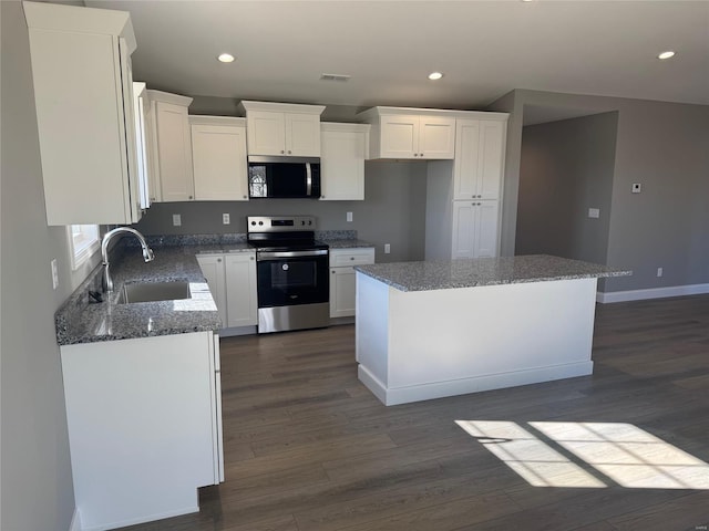 kitchen with white cabinetry, sink, stainless steel appliances, stone countertops, and a kitchen island