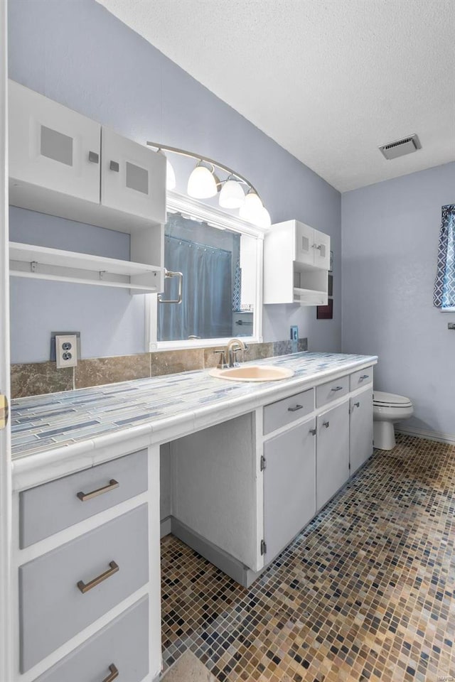 bathroom featuring a textured ceiling, vanity, and toilet