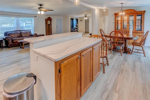 kitchen with a kitchen island, light wood-type flooring, pendant lighting, and ceiling fan