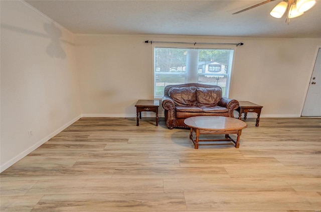 sitting room with light wood-type flooring, crown molding, and ceiling fan