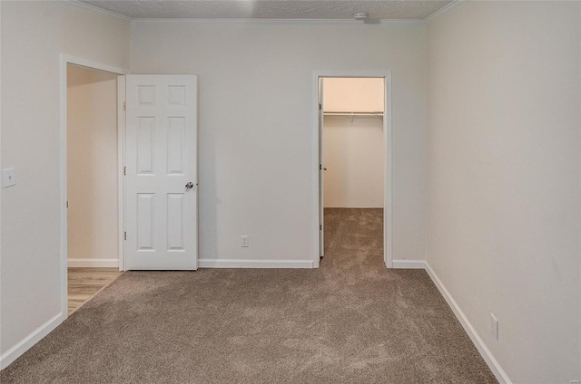 unfurnished bedroom with light carpet, a textured ceiling, a closet, and a walk in closet