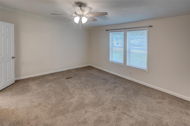 carpeted spare room featuring ceiling fan and crown molding