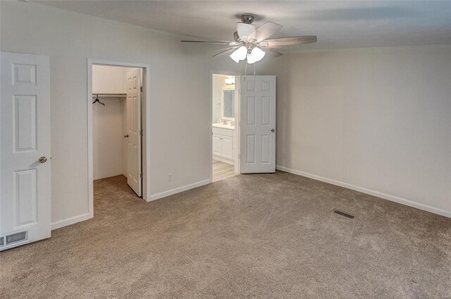 unfurnished bedroom with ceiling fan, a closet, light carpet, and a spacious closet