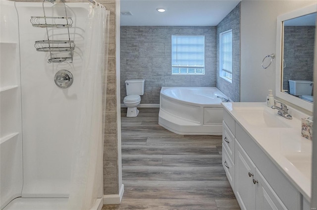 full bathroom featuring plus walk in shower, tile walls, hardwood / wood-style flooring, vanity, and toilet