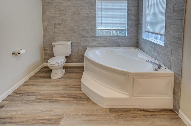 bathroom featuring tile walls, wood-type flooring, a tub, and toilet