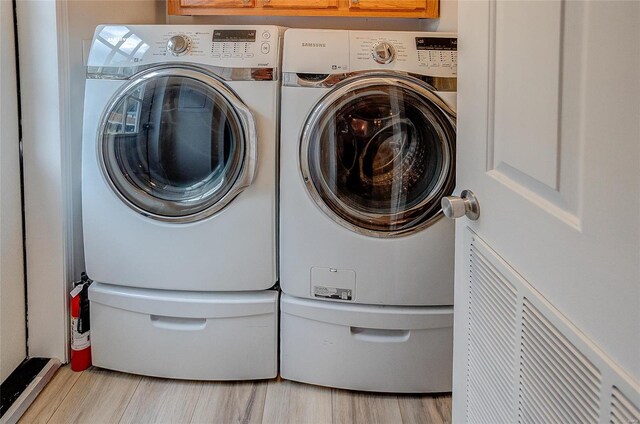 clothes washing area featuring light hardwood / wood-style floors and washing machine and clothes dryer