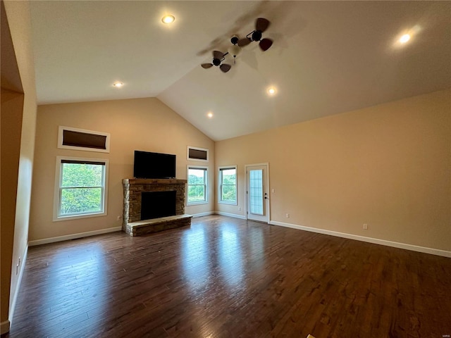 unfurnished living room with a stone fireplace, dark hardwood / wood-style floors, high vaulted ceiling, and a wealth of natural light