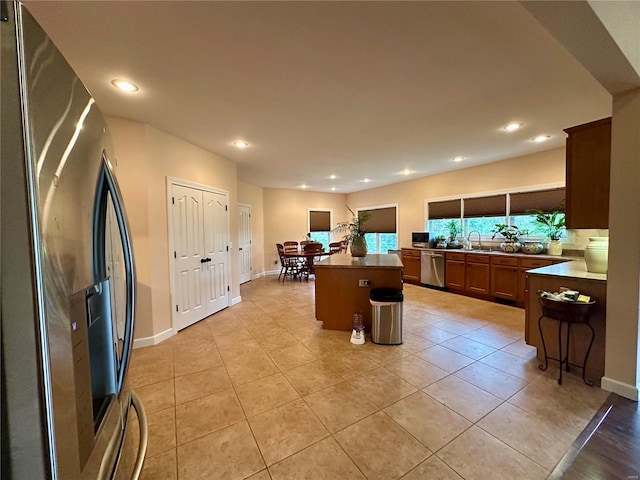 kitchen with appliances with stainless steel finishes, light tile patterned flooring, a center island, and a kitchen breakfast bar