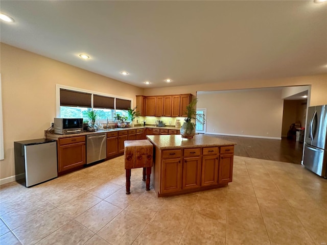 kitchen featuring appliances with stainless steel finishes, light tile patterned floors, dark stone counters, and a center island