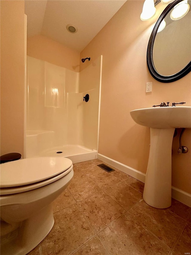 bathroom featuring a shower, vaulted ceiling, toilet, and tile patterned floors