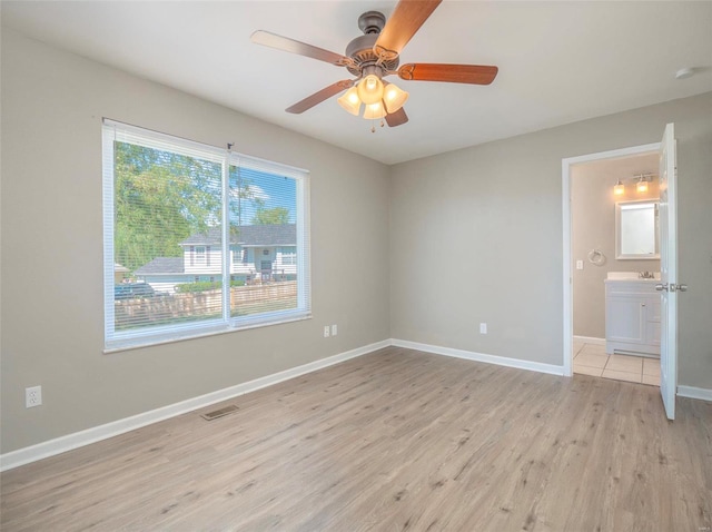 unfurnished bedroom featuring ceiling fan, ensuite bath, and light hardwood / wood-style floors