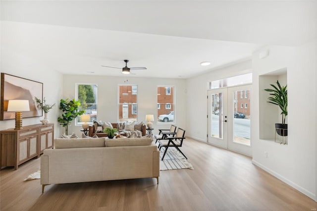 living room featuring light wood-type flooring, ceiling fan, and french doors