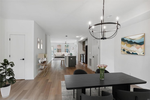 dining space with sink, hardwood / wood-style floors, and an inviting chandelier