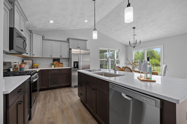 kitchen featuring light hardwood / wood-style floors, stainless steel appliances, lofted ceiling, a kitchen island with sink, and sink