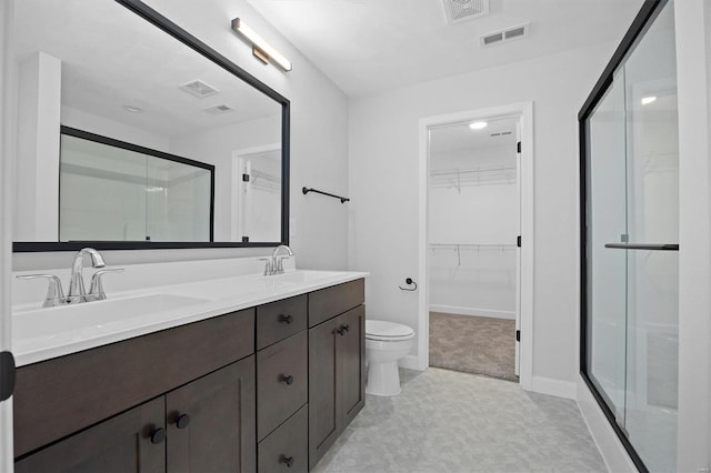 bathroom featuring vanity, a shower with shower door, and toilet