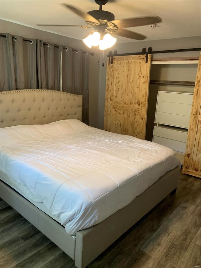 bedroom featuring ceiling fan, dark wood-type flooring, and a barn door