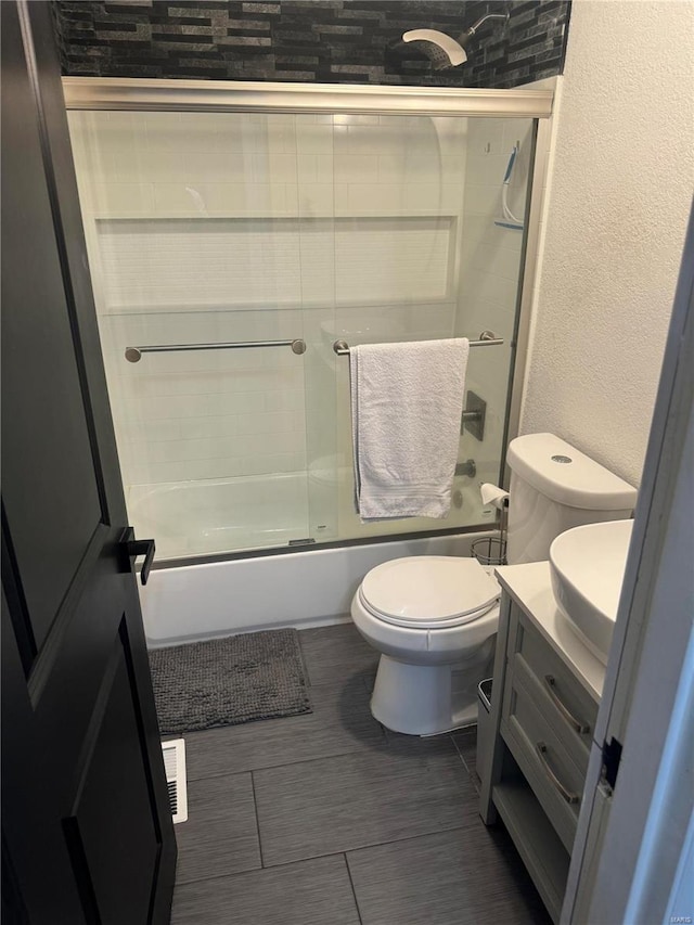 full bathroom with combined bath / shower with glass door, vanity, and toilet