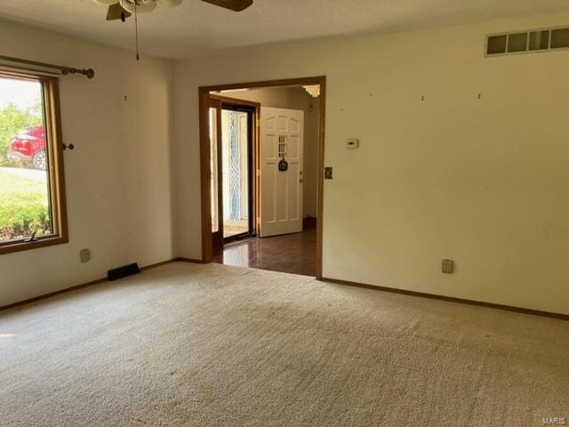 empty room featuring ceiling fan and dark carpet