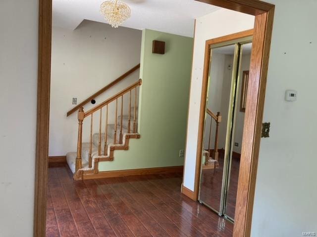 staircase with a chandelier and hardwood / wood-style floors