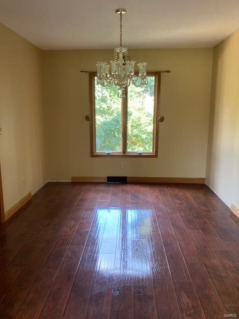 empty room featuring a chandelier and dark hardwood / wood-style flooring