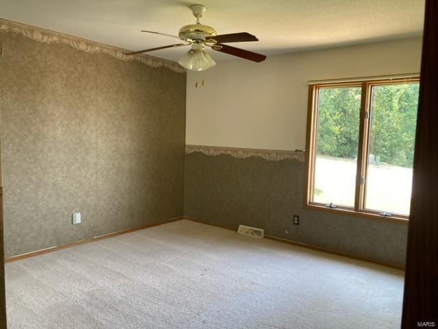 carpeted empty room featuring a textured ceiling and ceiling fan