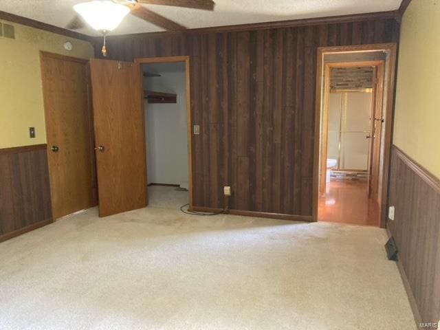 carpeted spare room with wood walls and ceiling fan