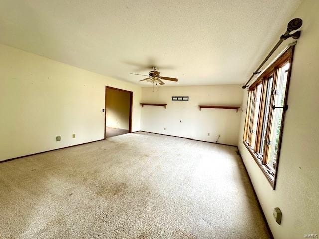 empty room with ceiling fan, carpet flooring, and a textured ceiling