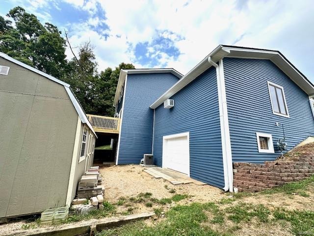 rear view of house featuring a garage and a wall mounted air conditioner