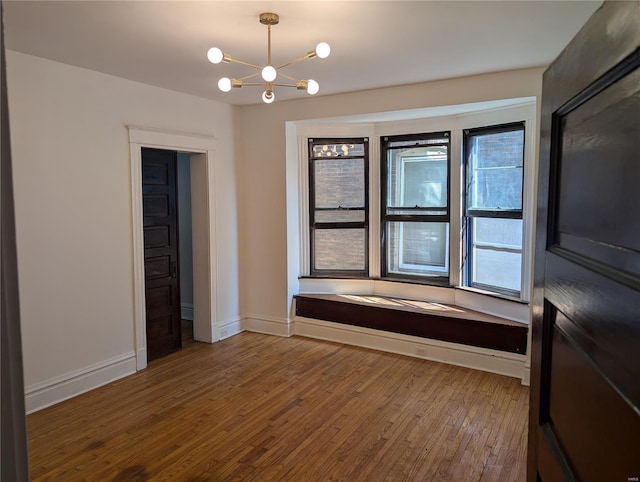 spare room with wood-type flooring and a notable chandelier