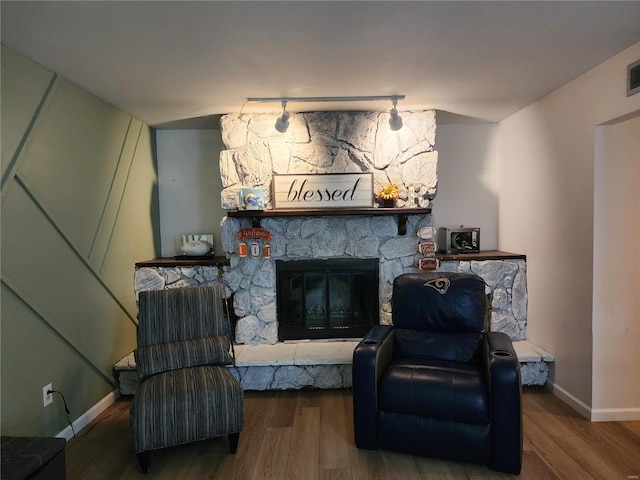 living area with a fireplace, rail lighting, and hardwood / wood-style flooring