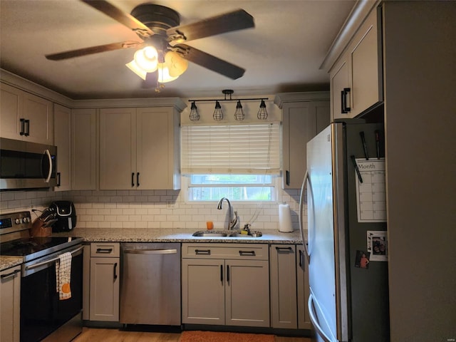 kitchen with decorative backsplash, appliances with stainless steel finishes, sink, and light stone counters