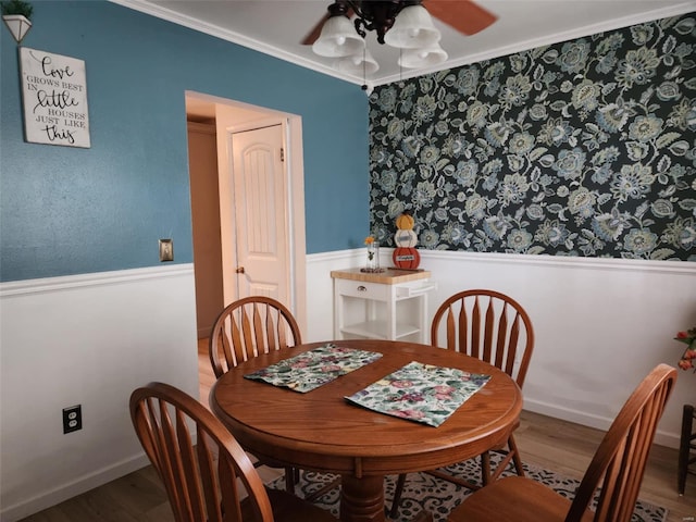 dining area with wood-type flooring, ornamental molding, and ceiling fan