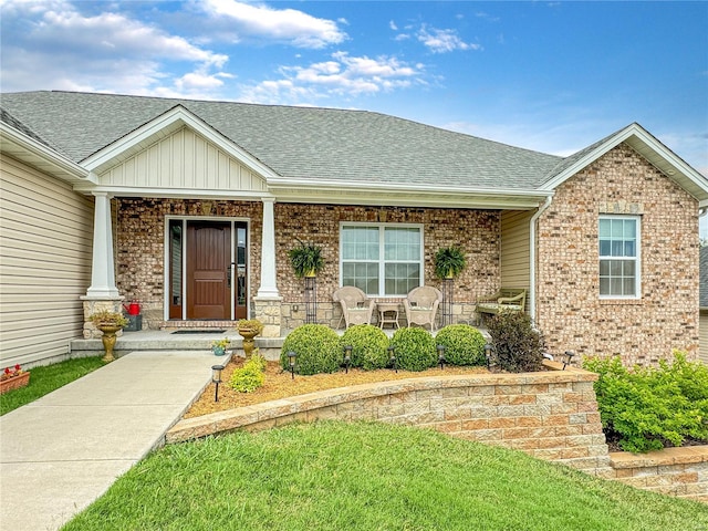 entrance to property with covered porch and a yard