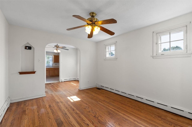 spare room with ceiling fan, light wood-type flooring, and a baseboard heating unit