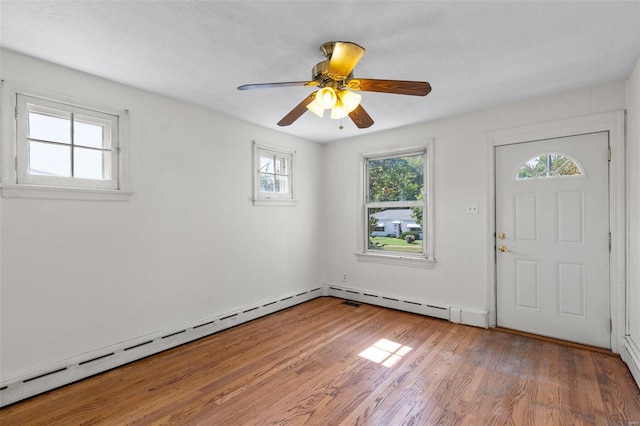 foyer entrance with a baseboard heating unit, light wood-type flooring, and ceiling fan