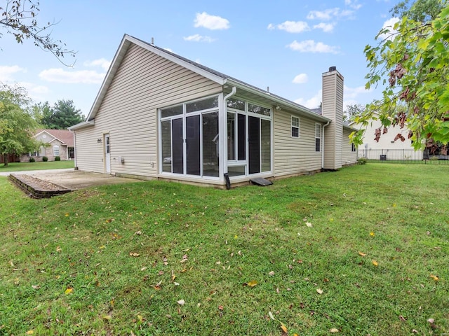 back of house with a sunroom, a yard, and a patio