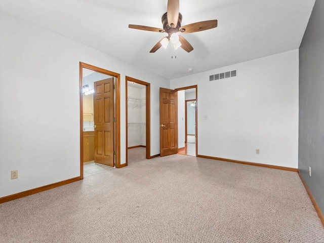 unfurnished bedroom with a spacious closet, a closet, ceiling fan, and light colored carpet