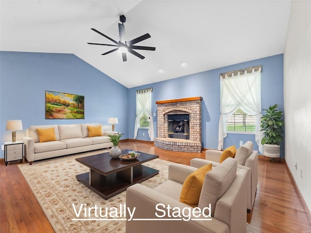 living room featuring hardwood / wood-style flooring, ceiling fan, lofted ceiling, and a fireplace