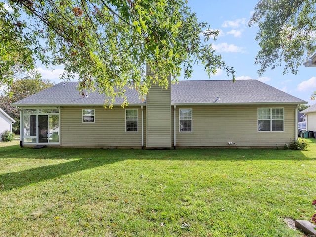 back of house with a lawn, a chimney, and a shingled roof