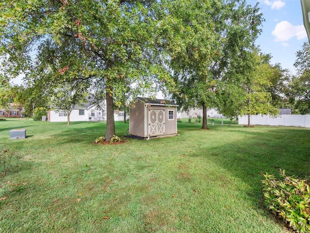 view of yard featuring a storage shed, an outdoor structure, and fence