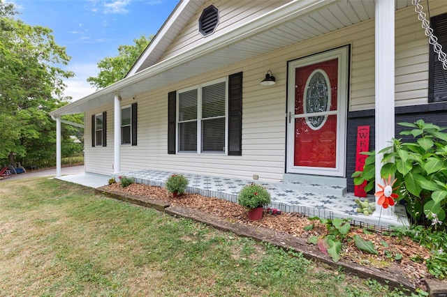 doorway to property with covered porch and a lawn