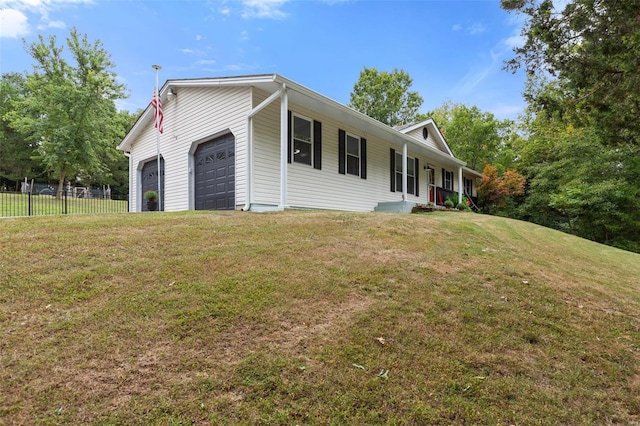 view of side of home with a yard, a garage, and covered porch